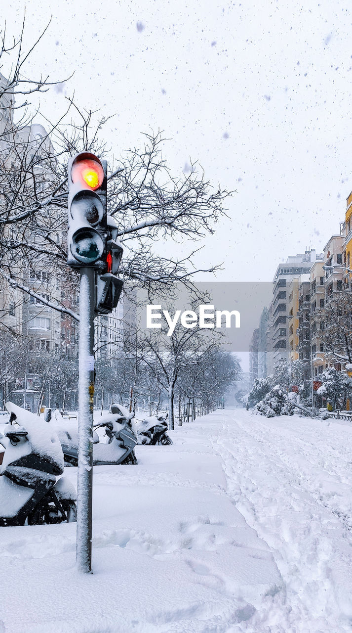 Snow covered street amidst buildings in city