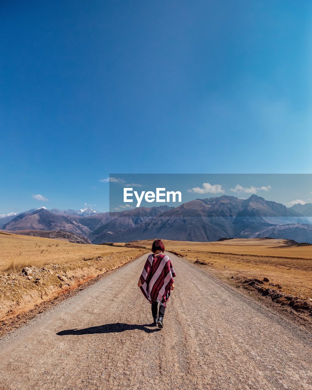 REAR VIEW OF WOMAN ON ROAD AGAINST MOUNTAIN