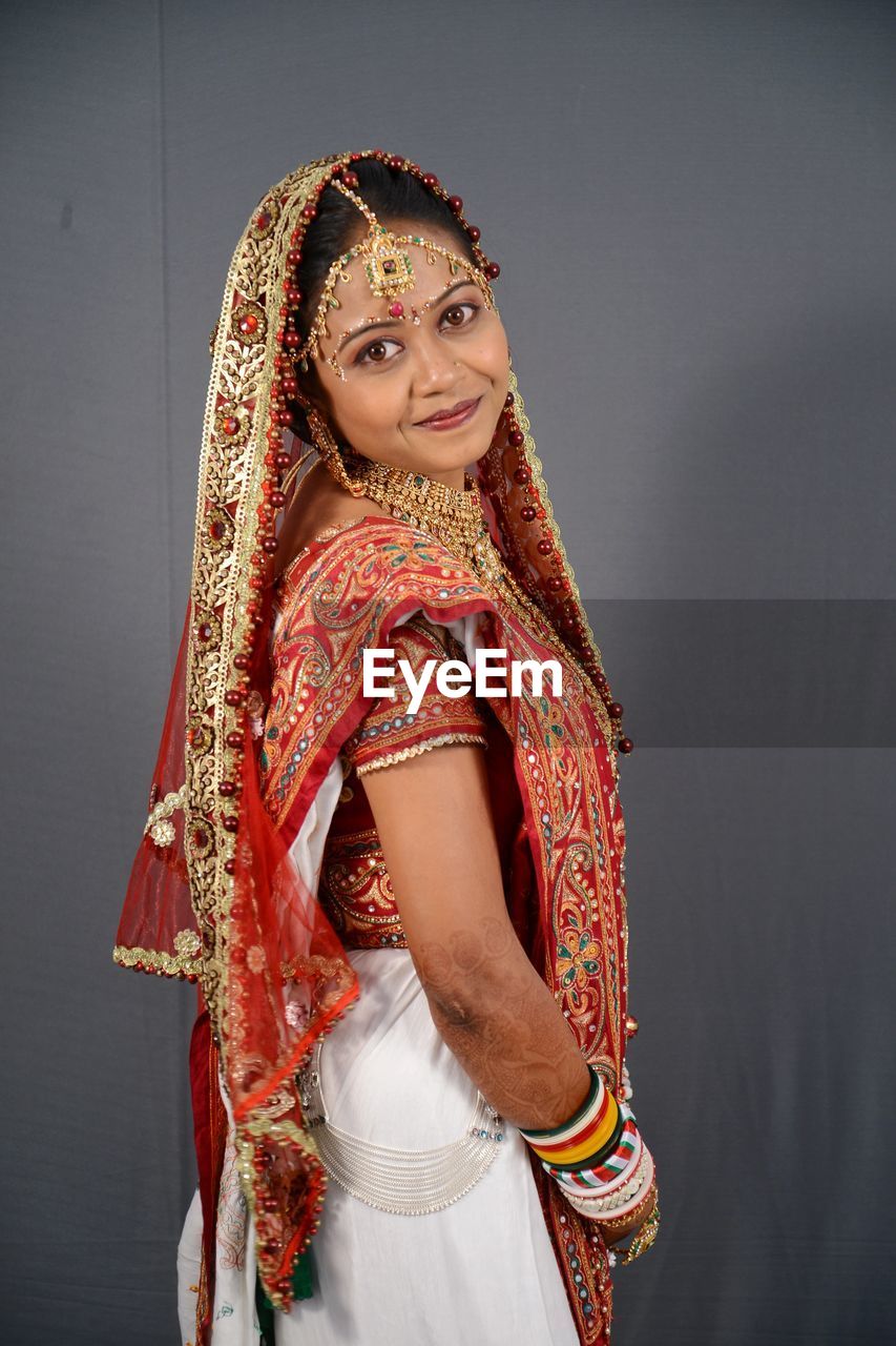 Portrait of smiling young bride standing against wall