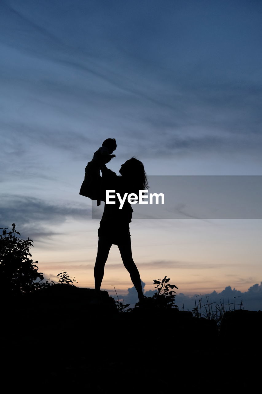 Silhouette couple standing against sky during sunset