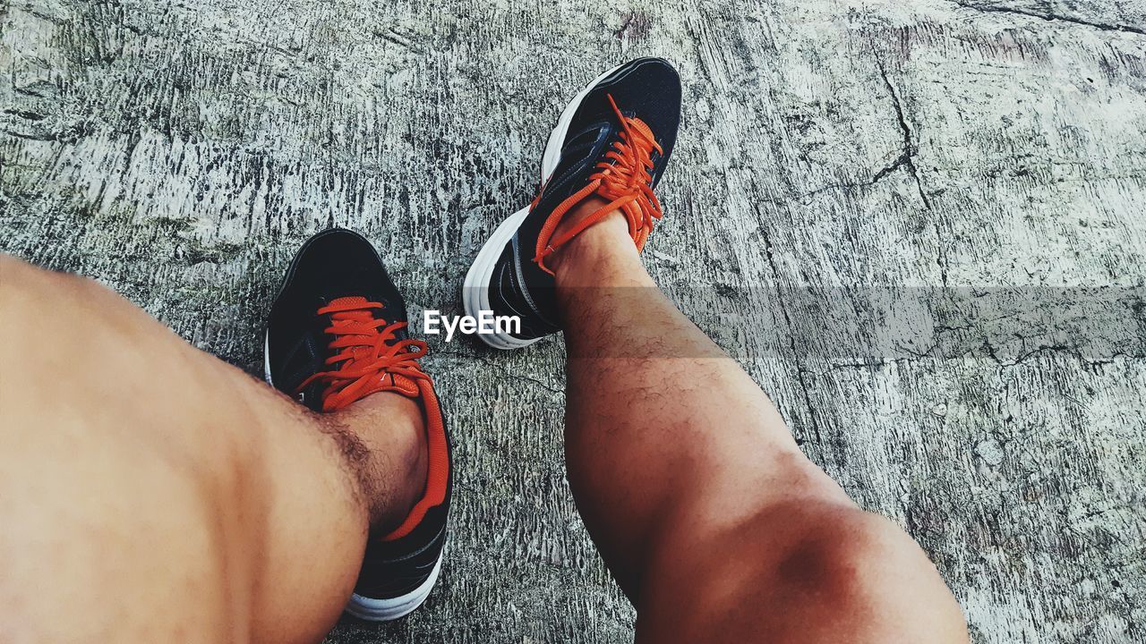 Low section of man wearing sports shoes on concrete footpath