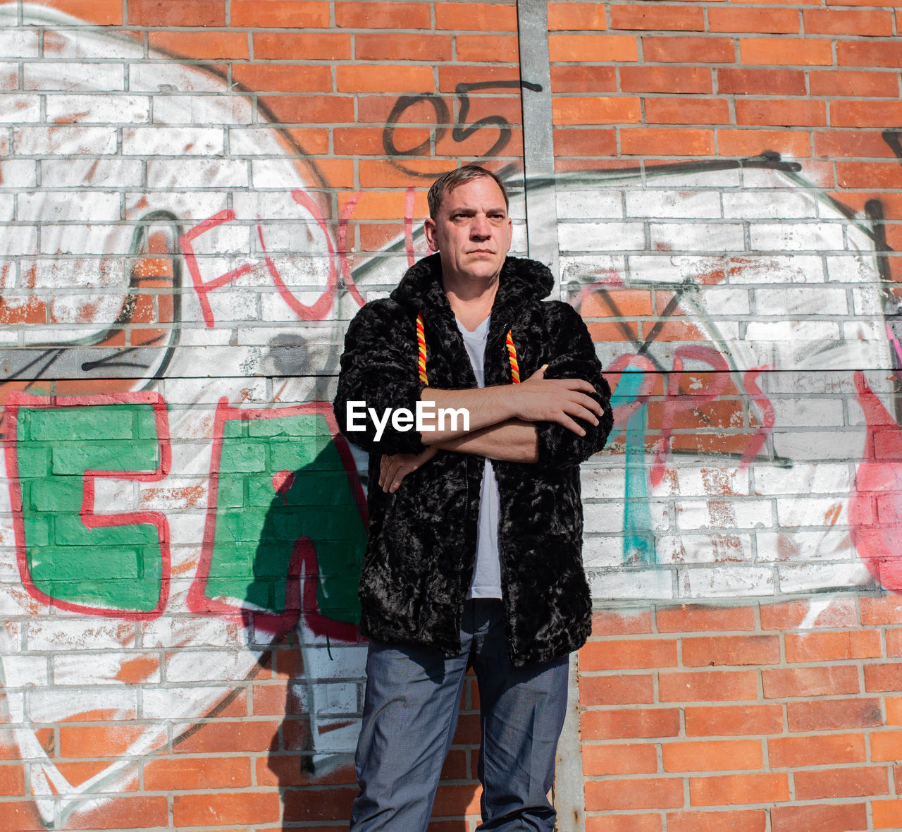 Fashionable mature man standing against graffiti wall