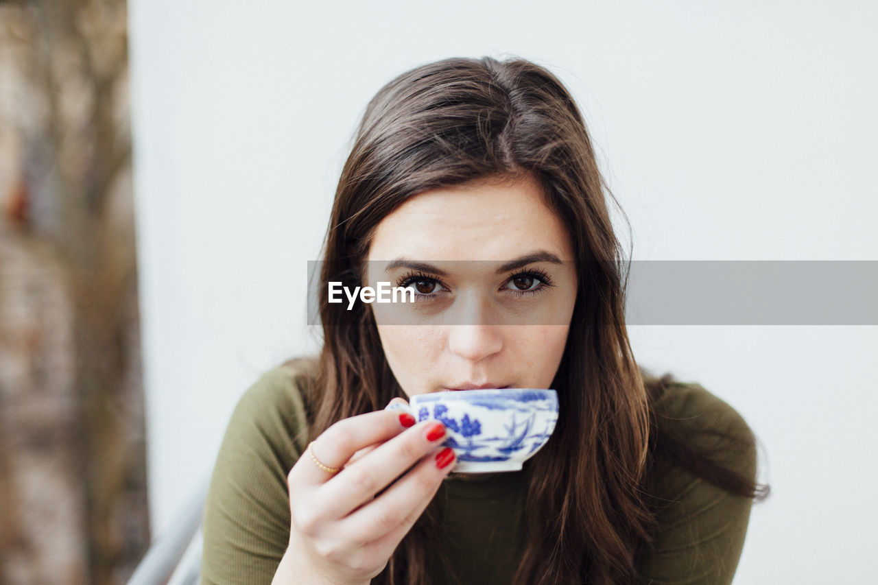 Close-up portrait of young woman having coffee at home