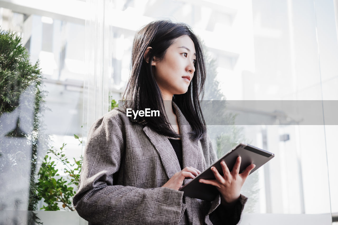 Portrait of beautiful chinese business woman using digital tablet in building office. technology