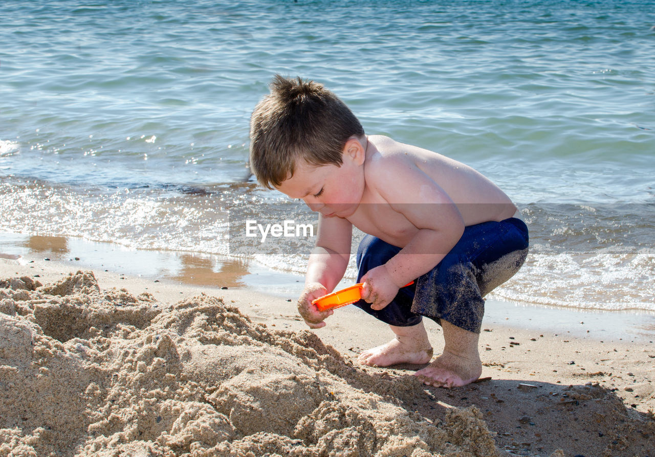 Toddler digging in the sand on a beach vacation
