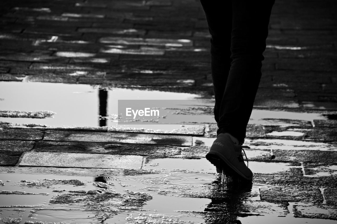 Low section of person walking on wet street