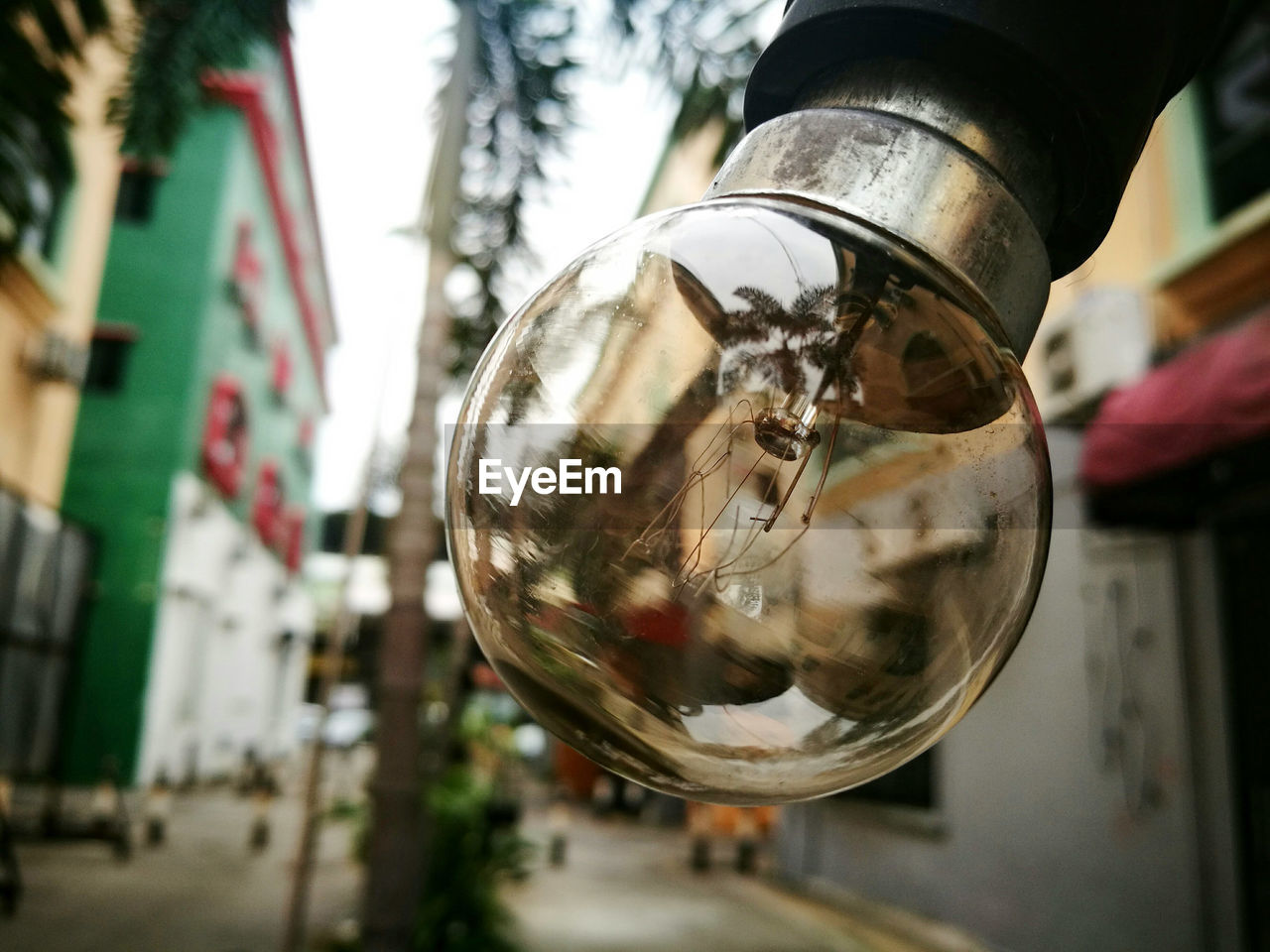 Close-up of light bulb with buildings in background