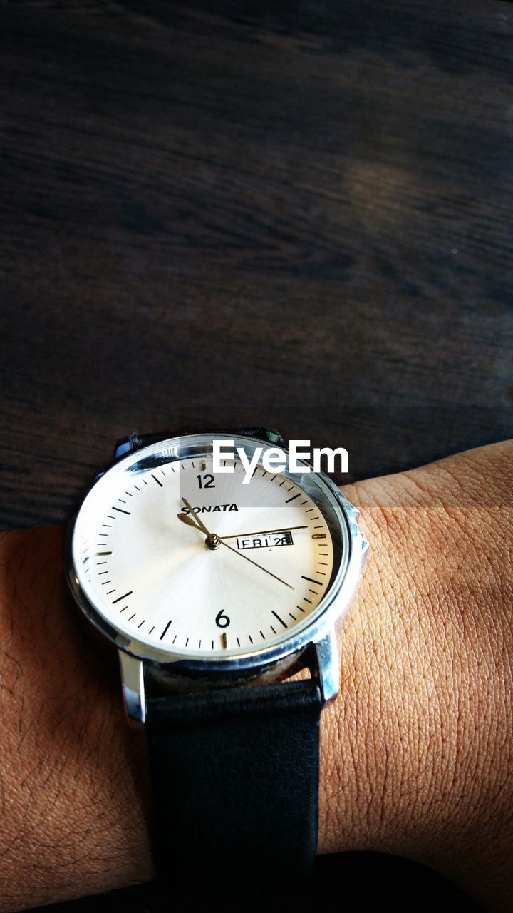 CLOSE-UP OF HAND HOLDING PAPER CLOCK