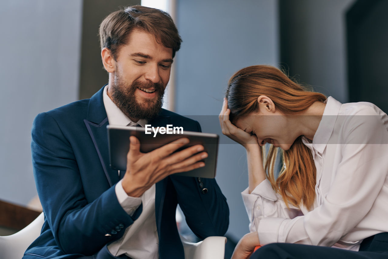 Young couple looking away while sitting on smart phone