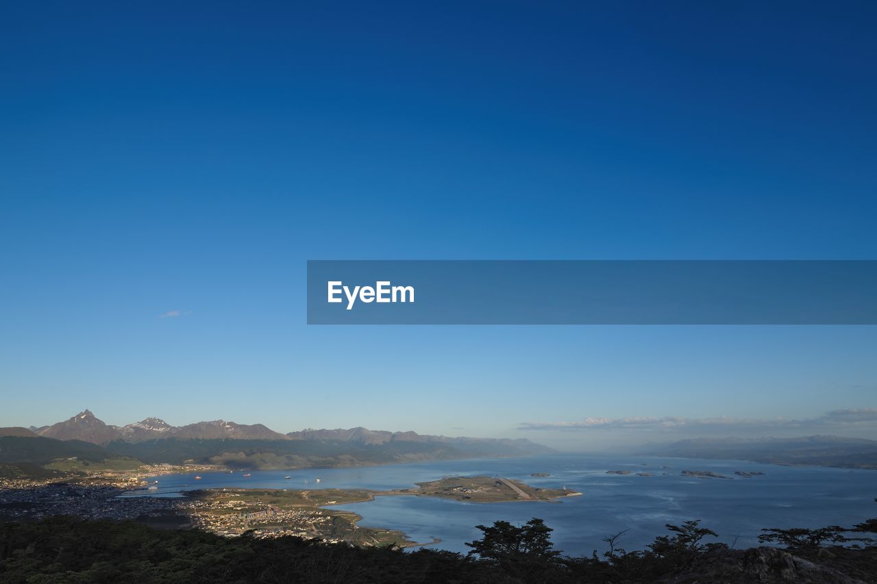 SCENIC VIEW OF SEA BY MOUNTAINS AGAINST CLEAR BLUE SKY