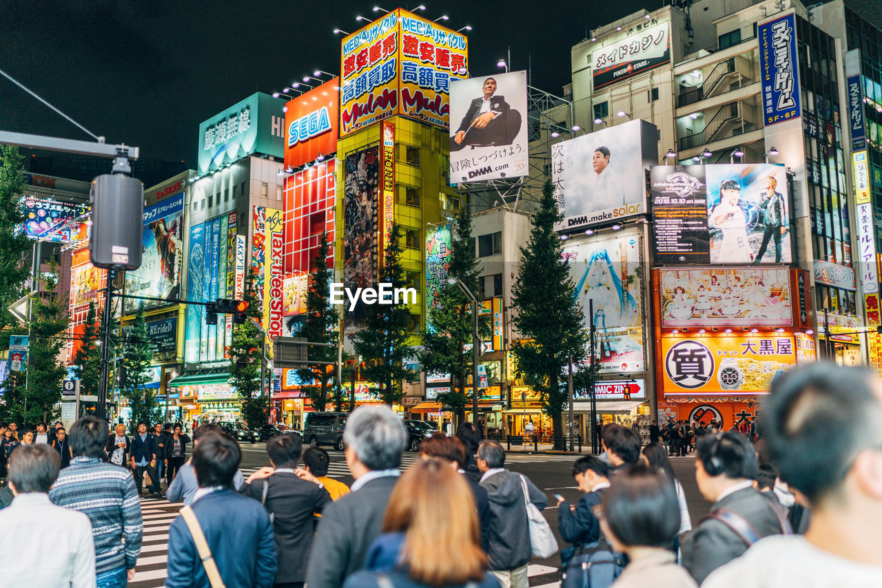 GROUP OF PEOPLE WALKING ON STREET IN CITY AT NIGHT