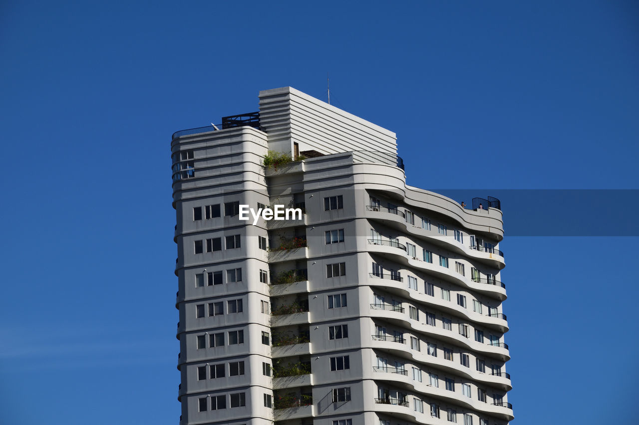 LOW ANGLE VIEW OF MODERN BUILDING AGAINST CLEAR BLUE SKY