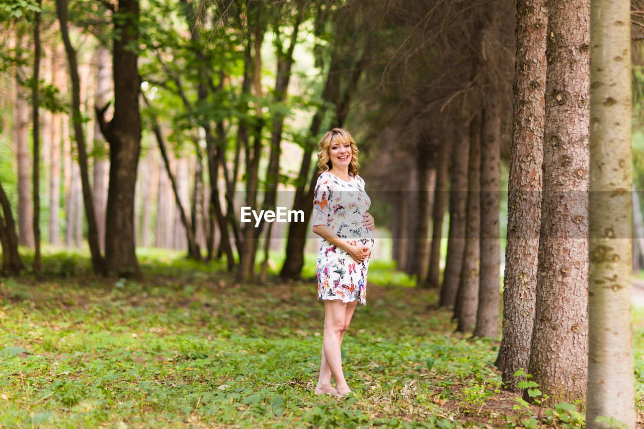 FULL LENGTH OF BOY STANDING ON TREE TRUNK