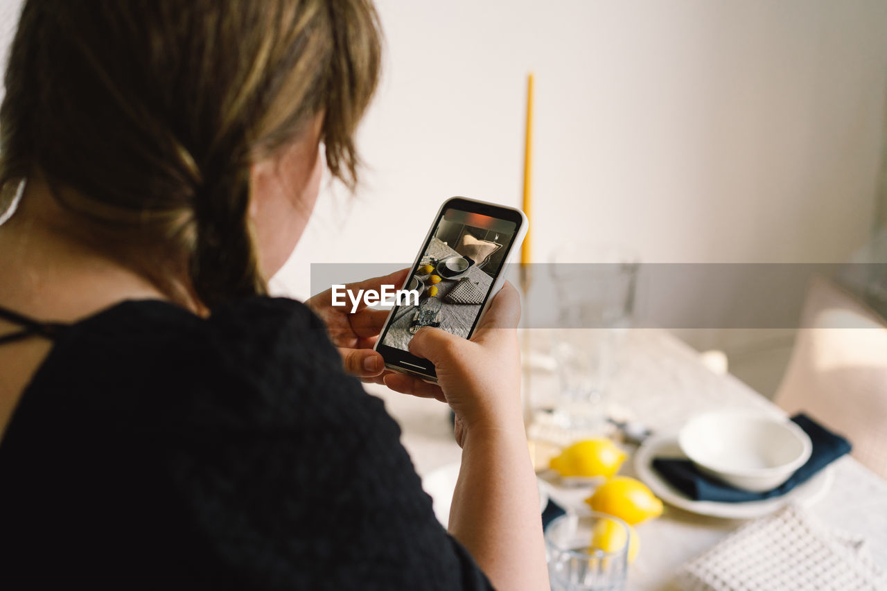 Video blog. a young woman is filming kitchen goods for her online store on her phone camera.