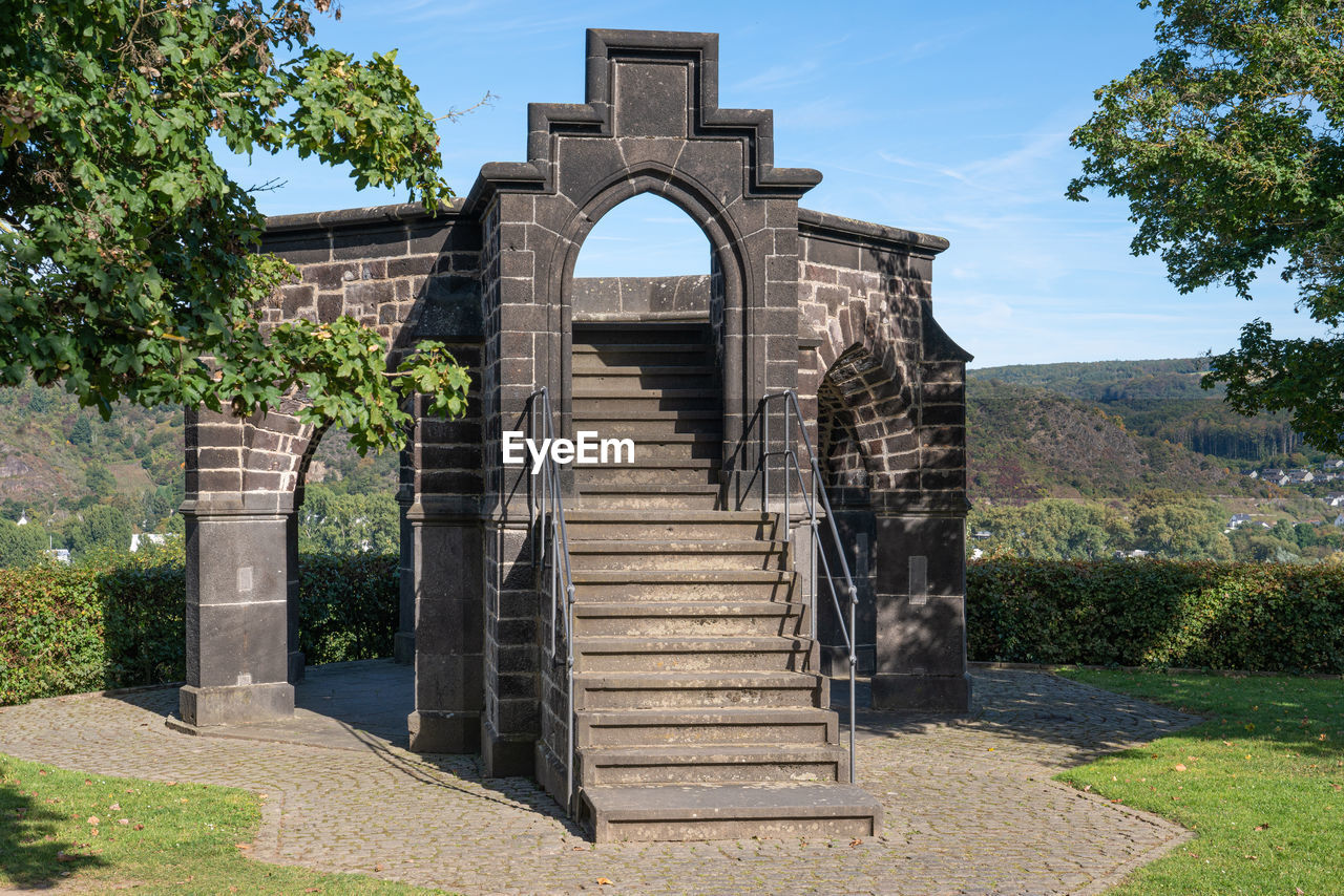 architecture, built structure, plant, arch, nature, tree, sky, entrance, gate, no people, estate, staircase, history, building exterior, travel destinations, the past, day, outdoors, building, sunlight, sunny, landmark, place of worship, memorial, religion, monument, grass, travel, blue, cloud, ruins