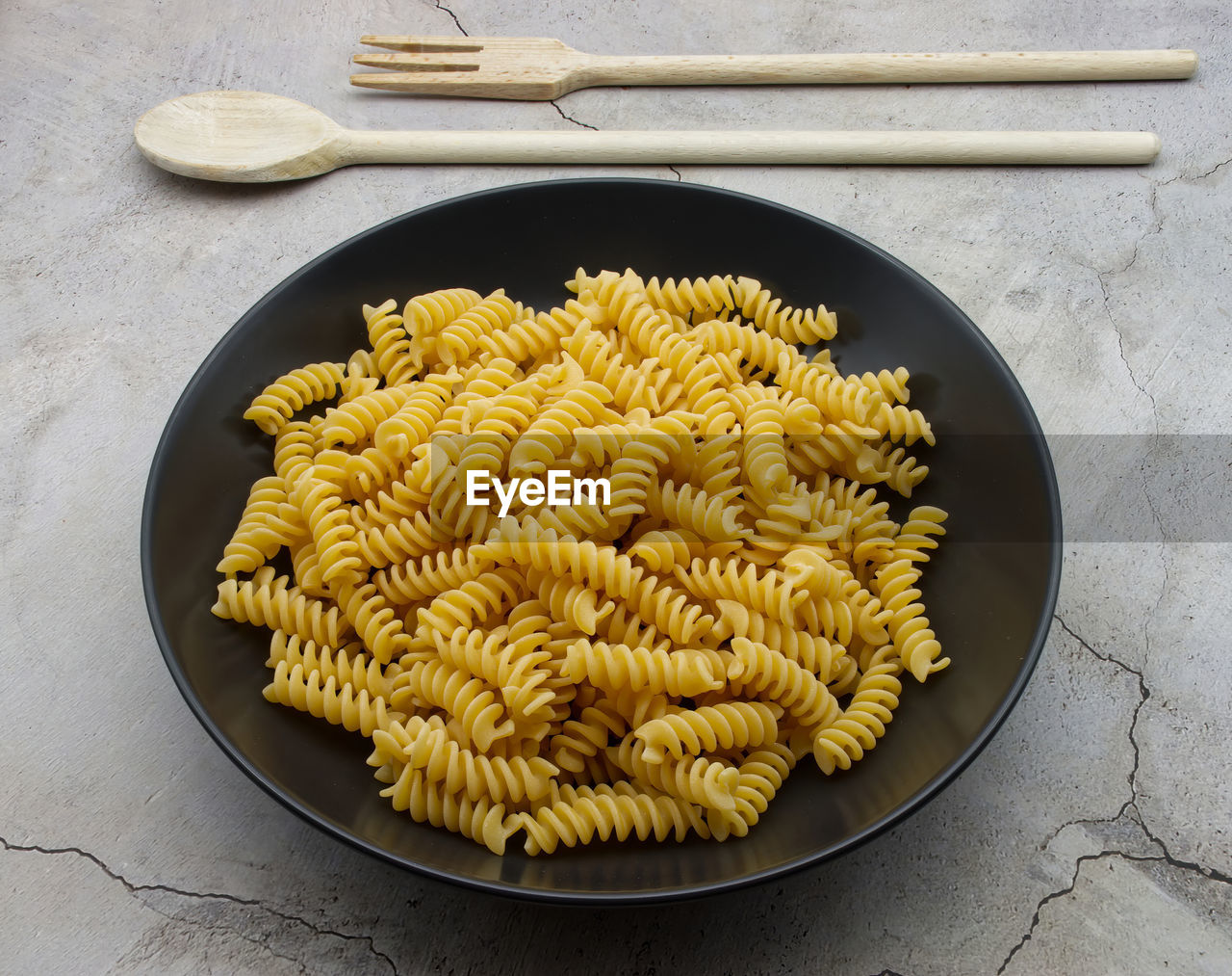 Raw italian fusilli pasta in a black dish. traditional italian cuisine.