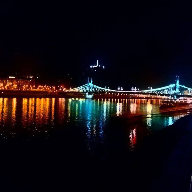 ILLUMINATED BRIDGE OVER RIVER AT NIGHT