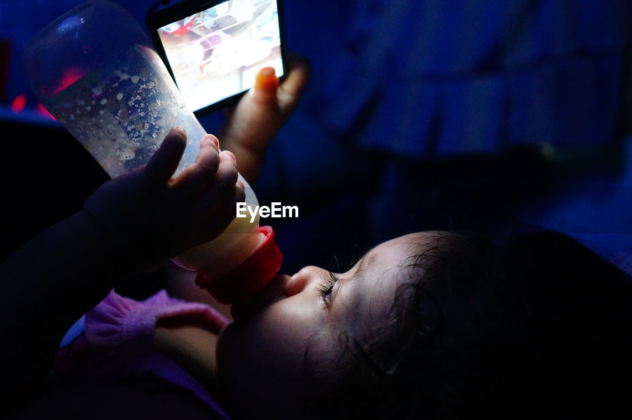 Close-up of girl using smart phone while drinking milk