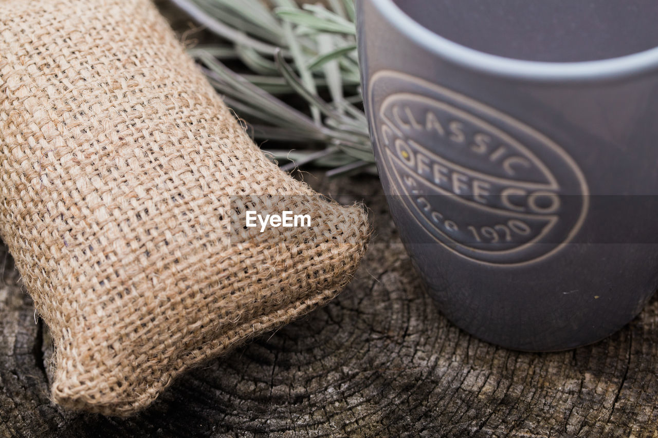 High angle view of coffee cup with sack on wooden table