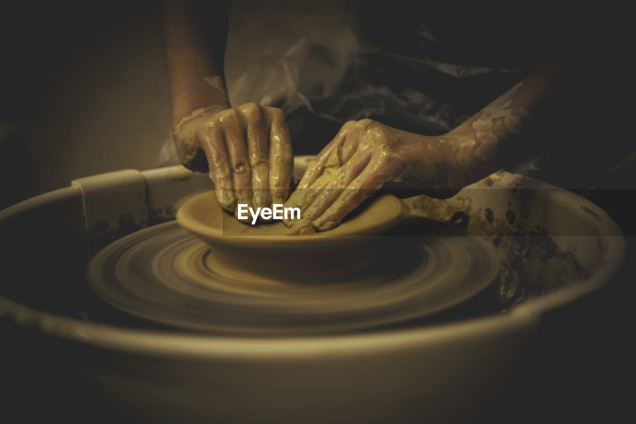 Midsection of person making pottery in workshop