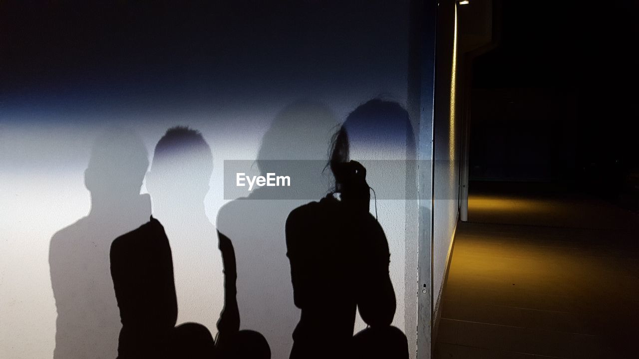 SILHOUETTE PEOPLE STANDING AGAINST SKY SEEN THROUGH GLASS