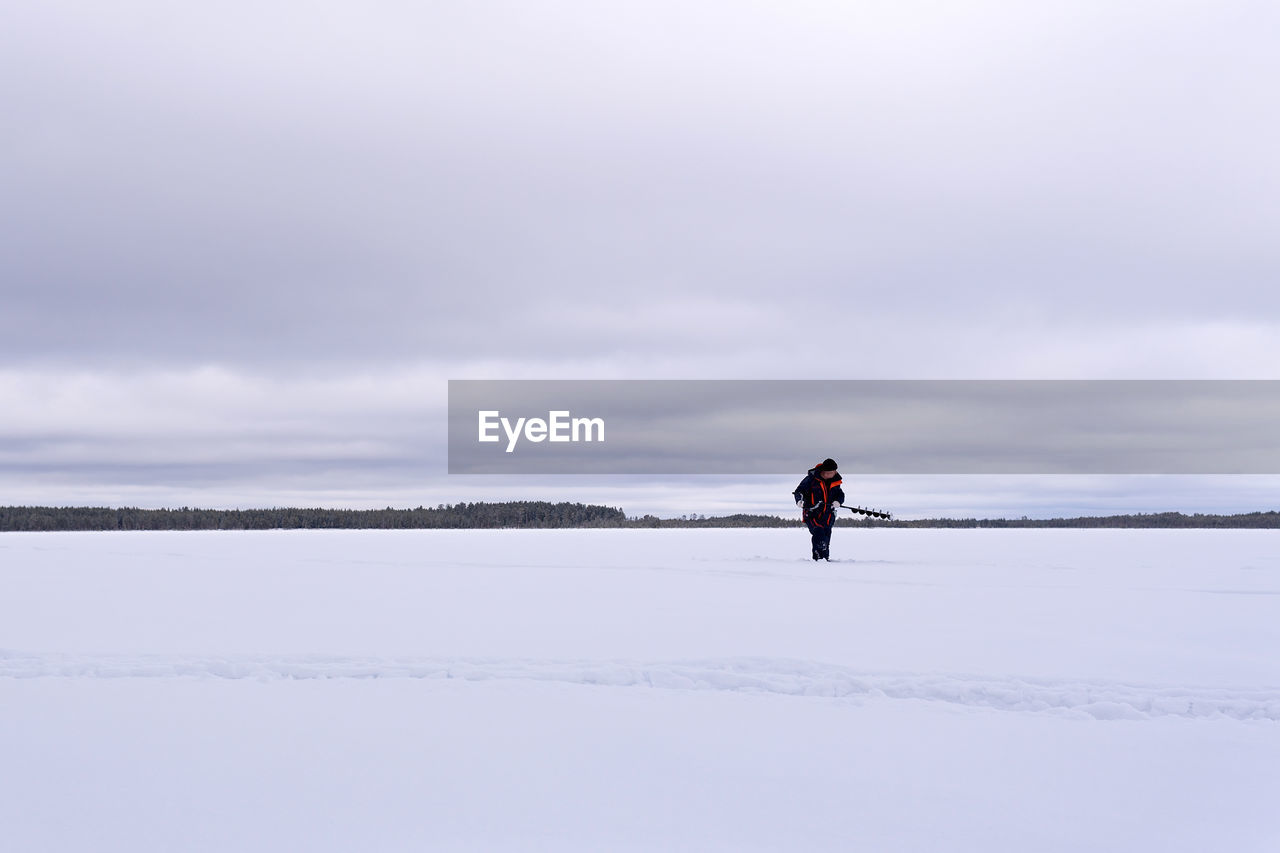 FULL LENGTH OF MAN ON SNOW COVERED LANDSCAPE AGAINST SKY