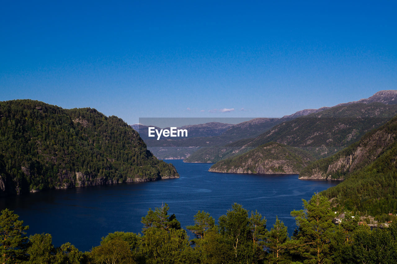 Scenic view of lake and mountains against clear blue sky