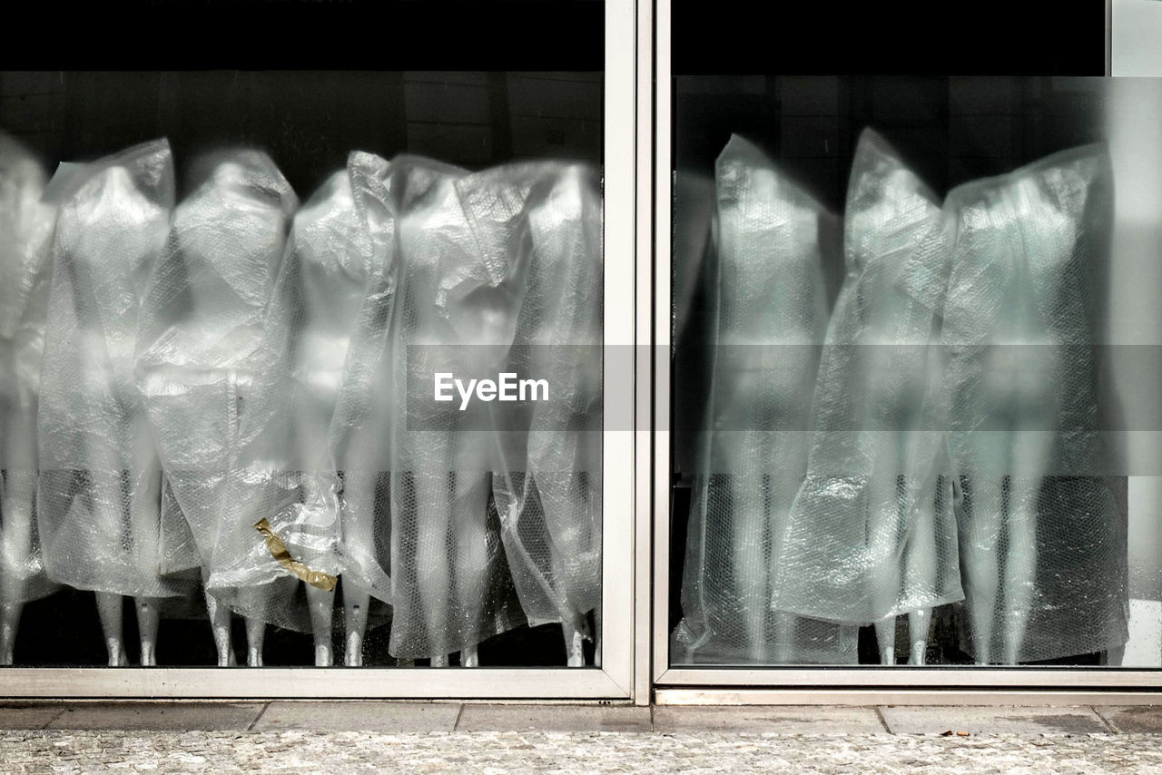 Mannequins wrapped in plastic seen from store window