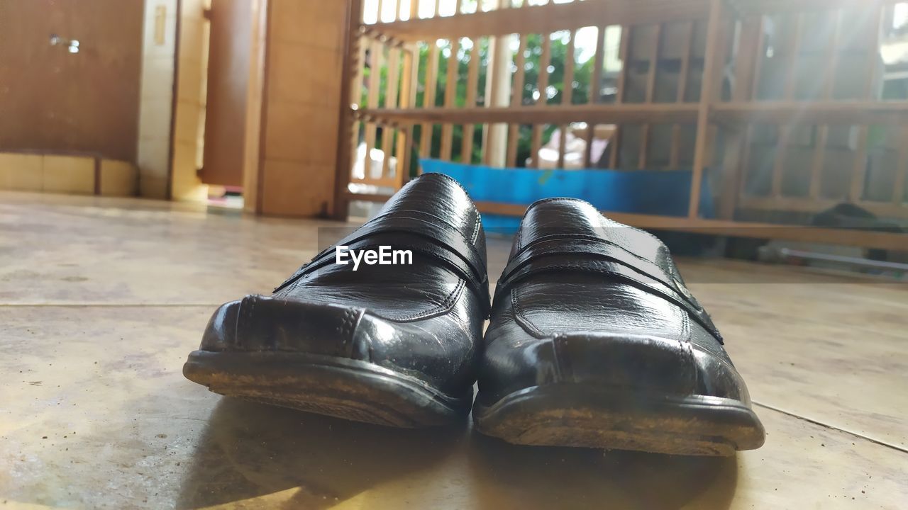 footwear, shoe, indoors, flooring, absence, sunlight, day, pair, architecture, human leg, relaxation, lifestyles, sneakers, leather, home interior, focus on foreground, outdoor shoe