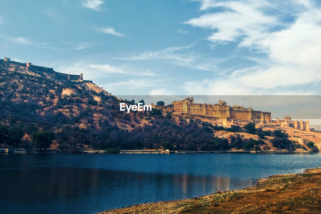 Ancient vintage palace by lake against sky in city