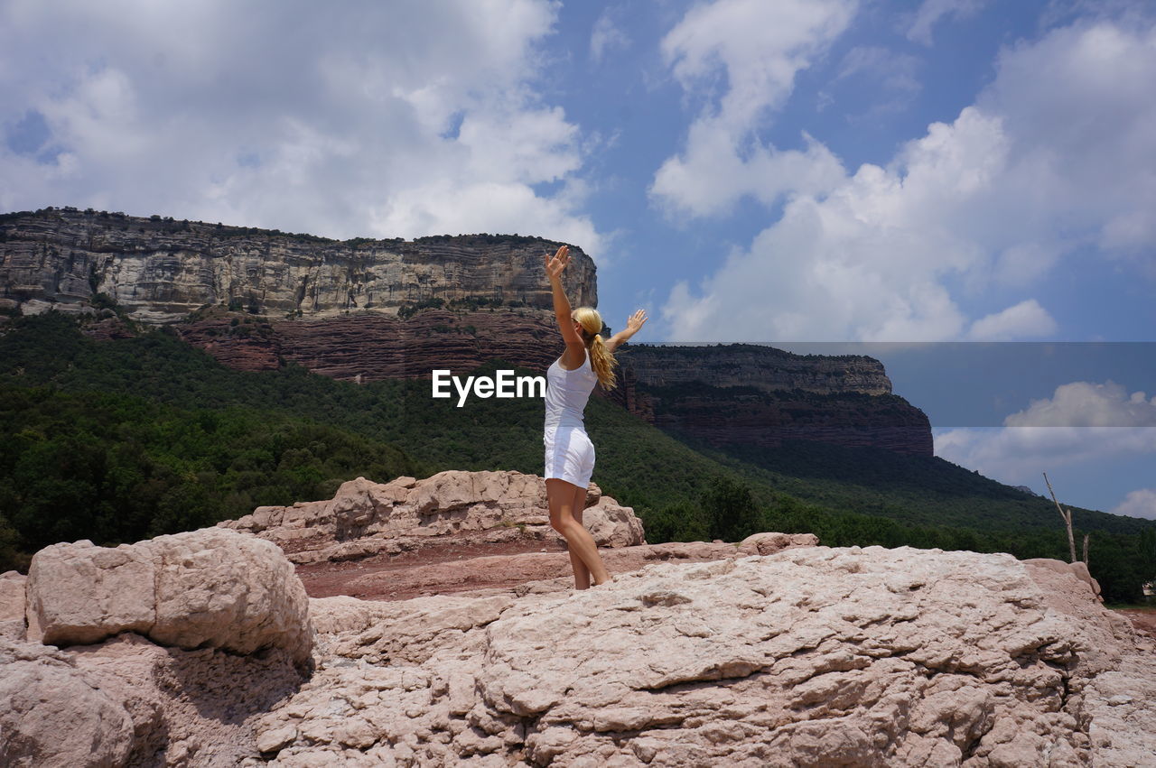 Woman standing on rock against sky