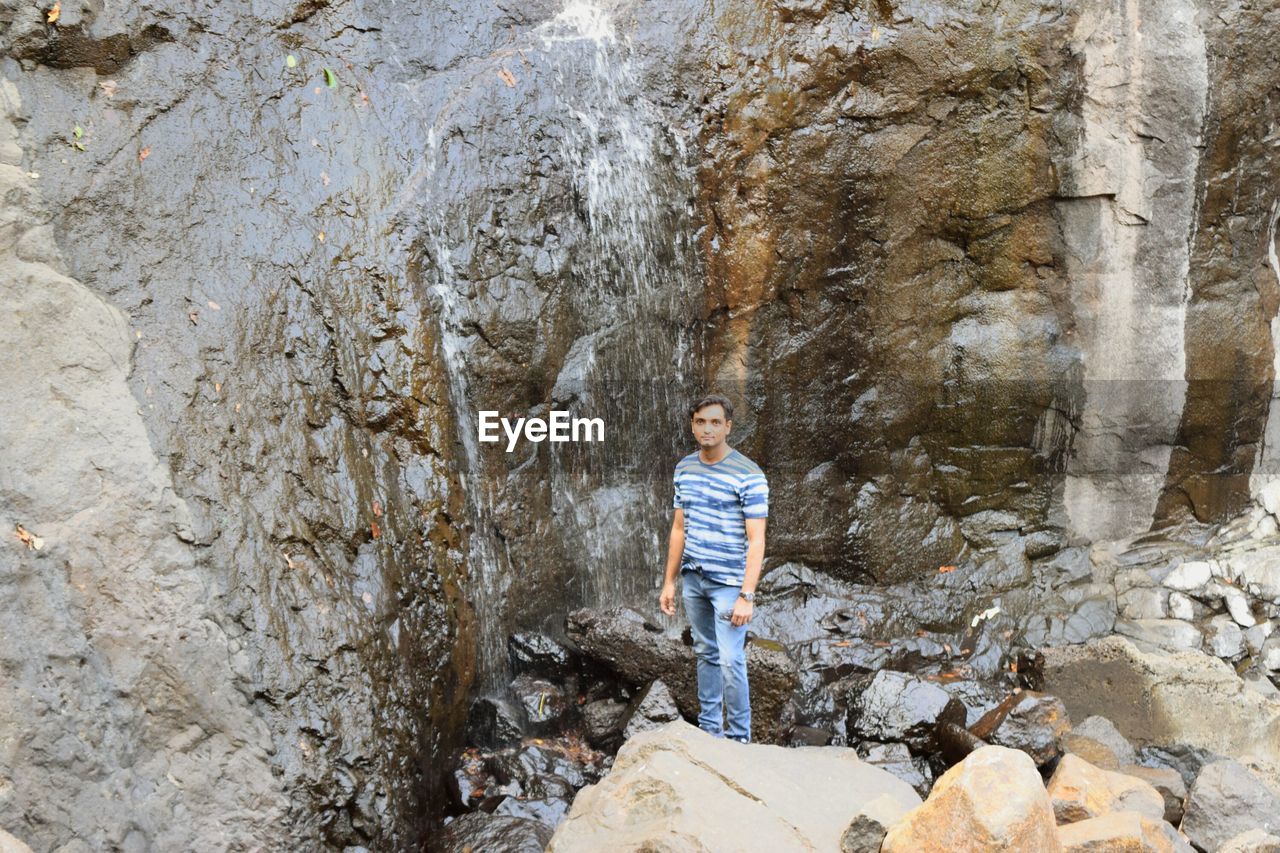 BOY STANDING ON ROCKS