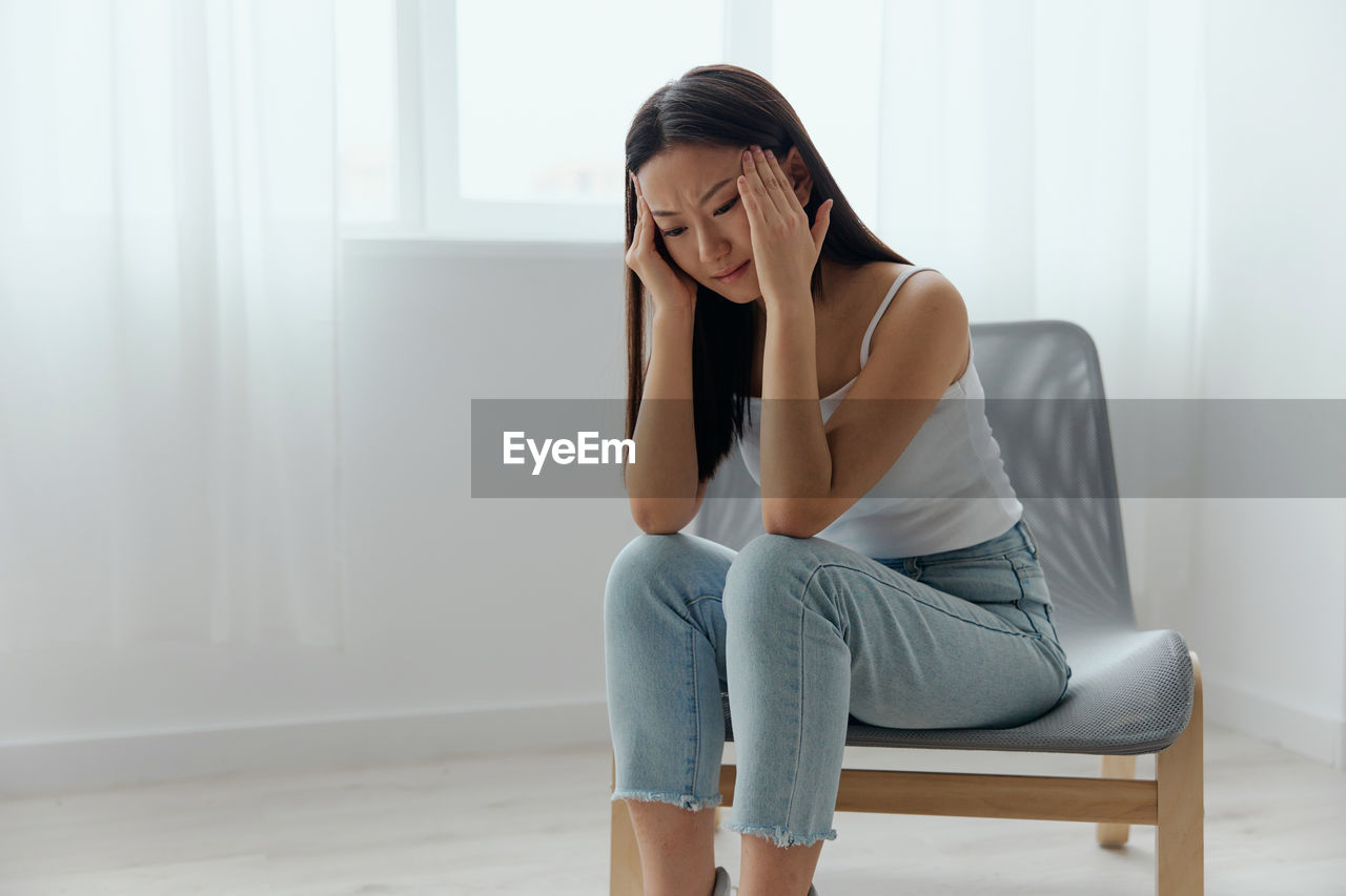 Woman with headache sitting on chair