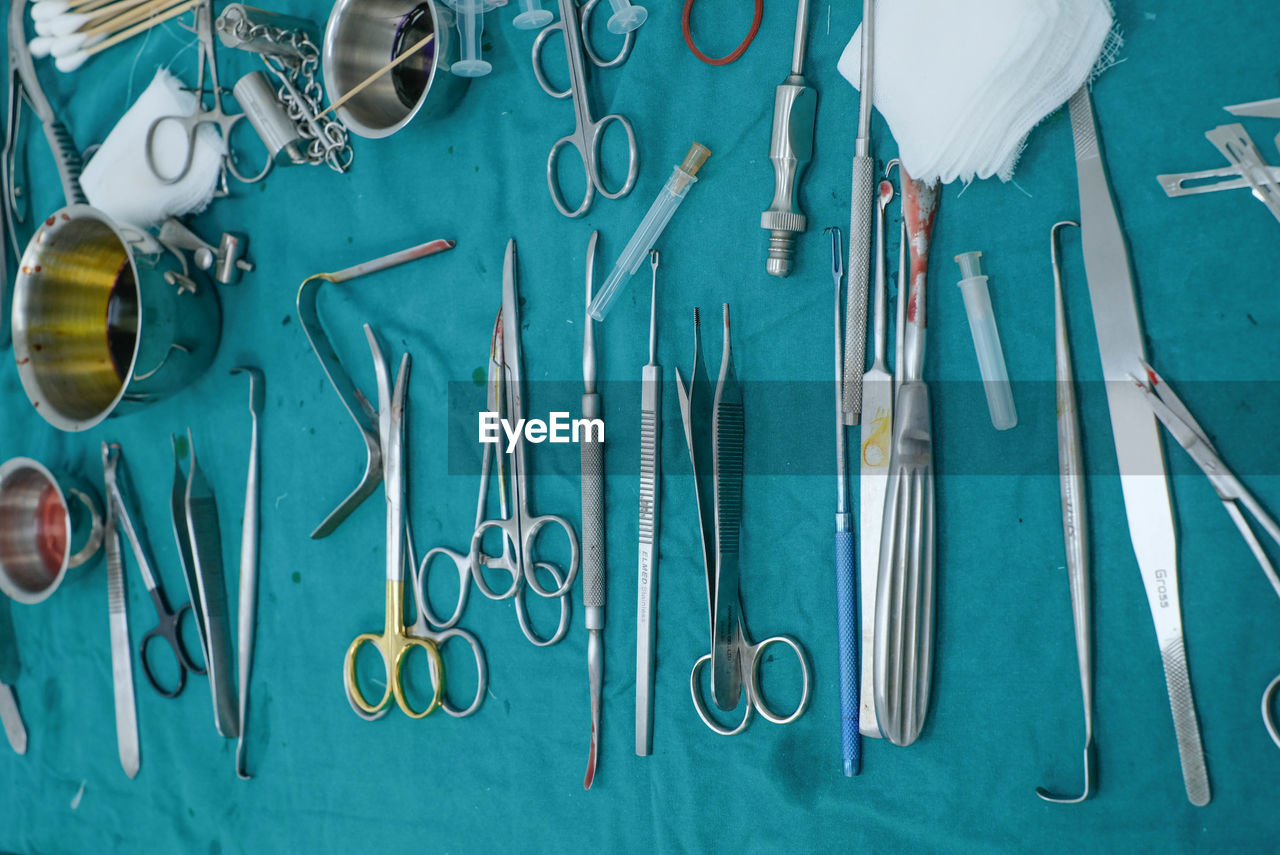 medical equipment, scissors, blue, no people, indoors, large group of objects, surgical equipment, variation, work tool, still life, directly above, high angle view, metal, healthcare and medicine, equipment, table, knolling - concept