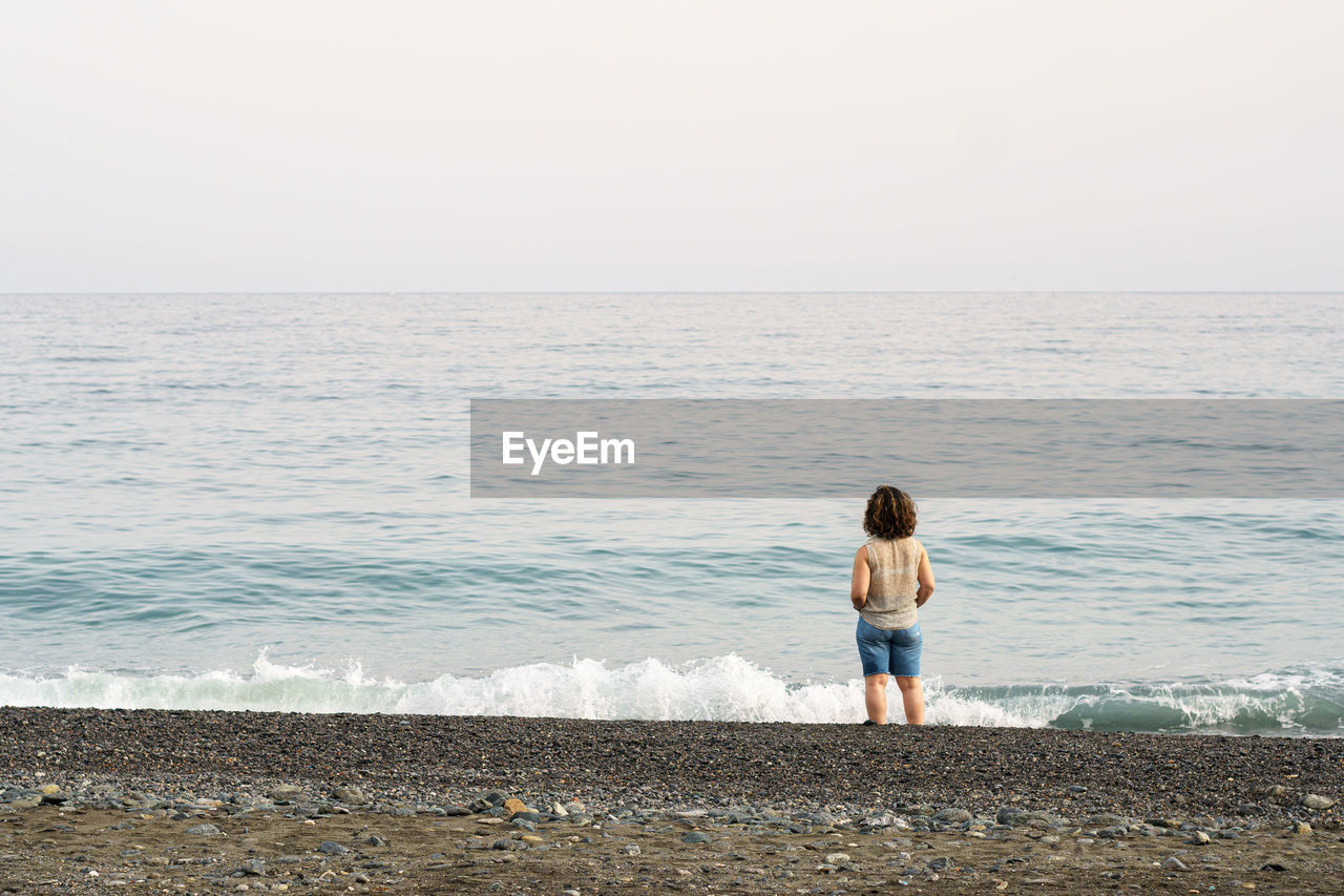 Rear view of woman standing at beach