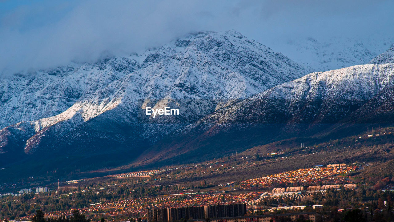 AERIAL VIEW OF SNOWCAPPED MOUNTAIN RANGE AGAINST SKY