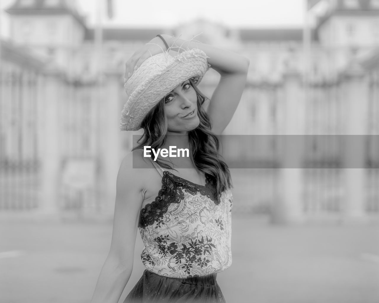 Young woman wearing hat standing against built structure