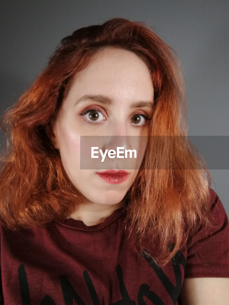 Close-up portrait of beautiful redhead woman over gray background