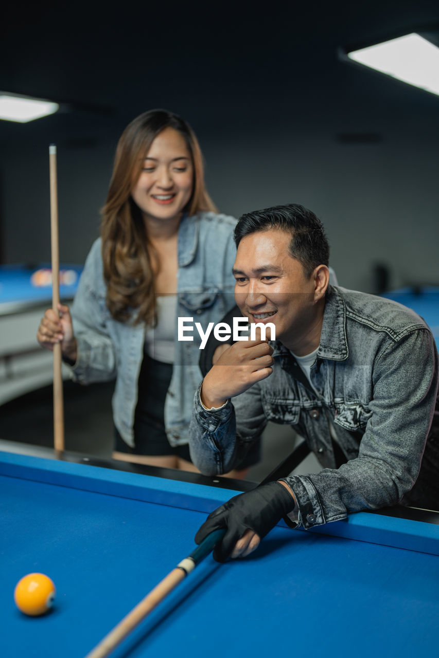 portrait of smiling friends playing pool at home