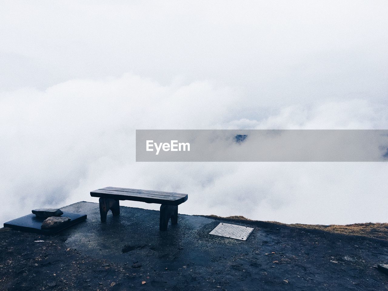 Empty bench on mountain peak during foggy weather