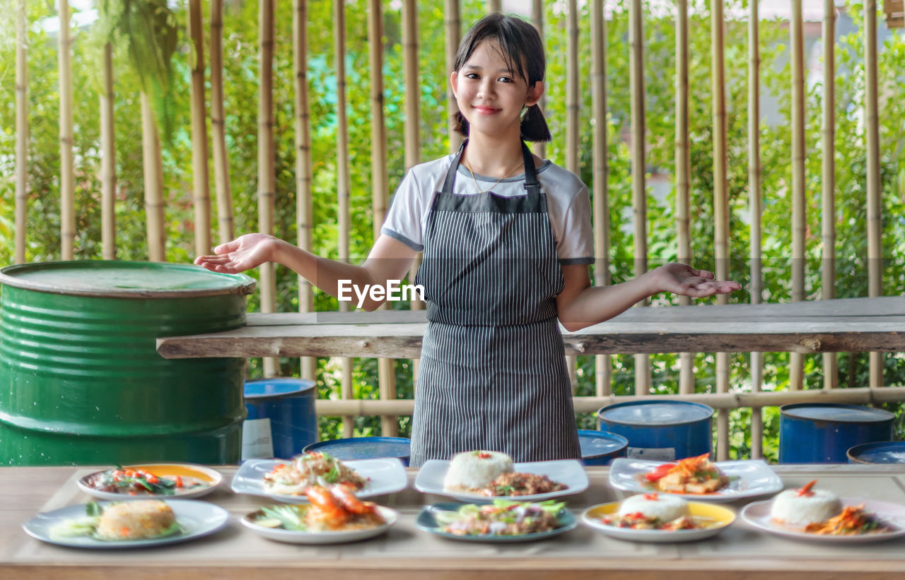 WOMAN HOLDING FOOD ON TABLE AT RESTAURANT