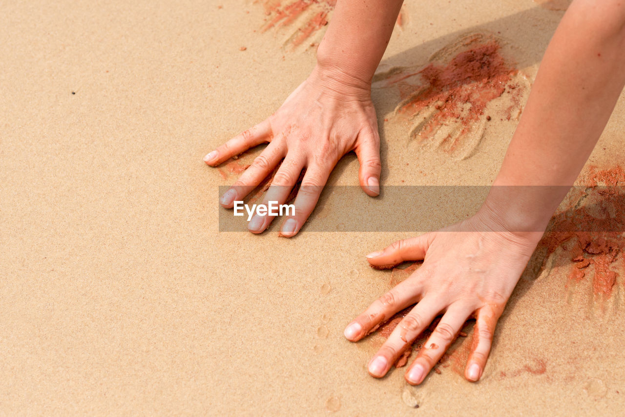 Cropped image of hands on sand at beach