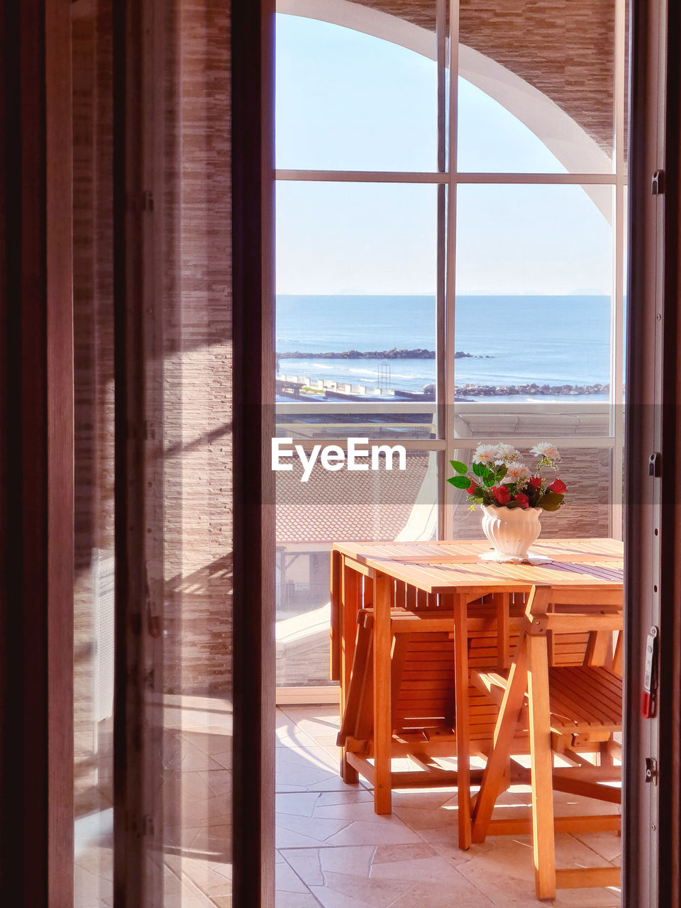Chairs and table by sea seen through window
