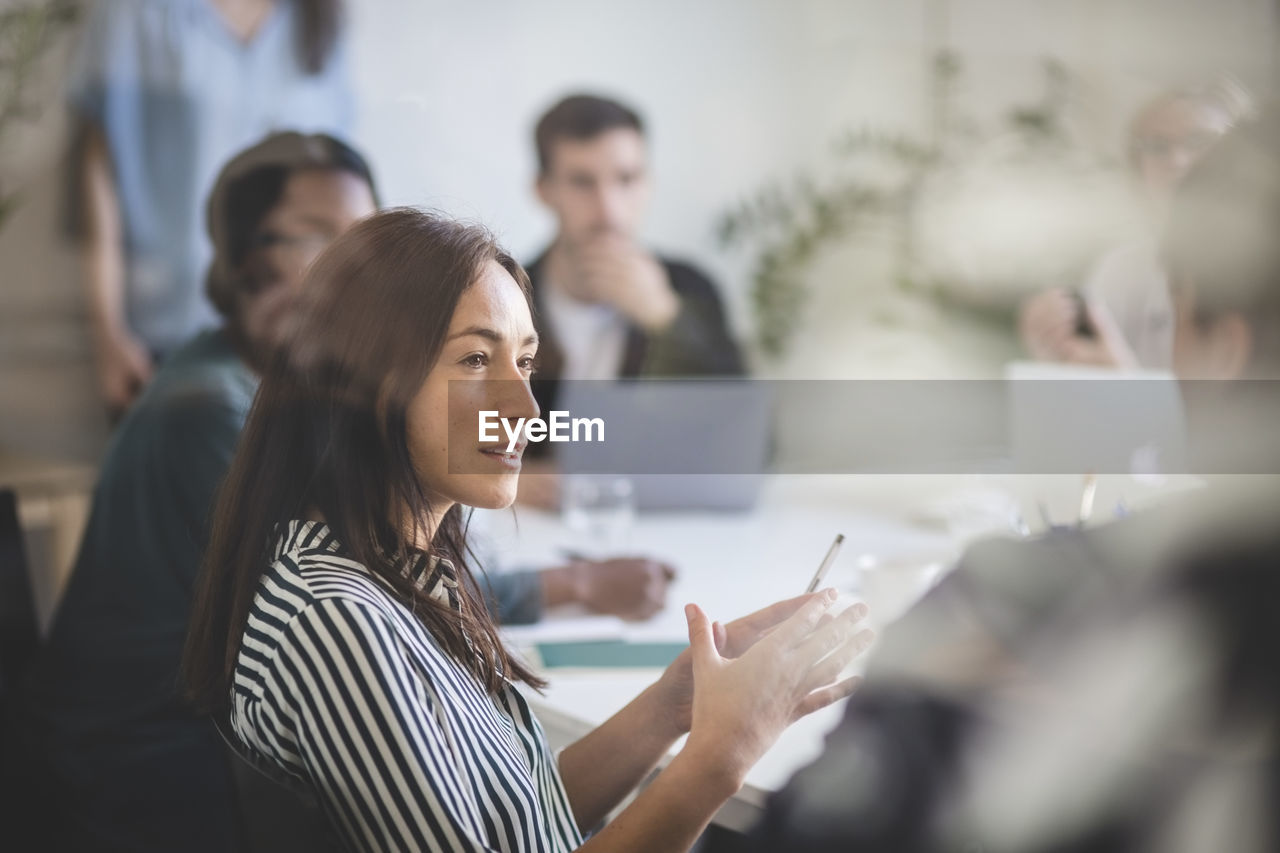 Businesswoman explaining colleagues during brainstorming session in creative office