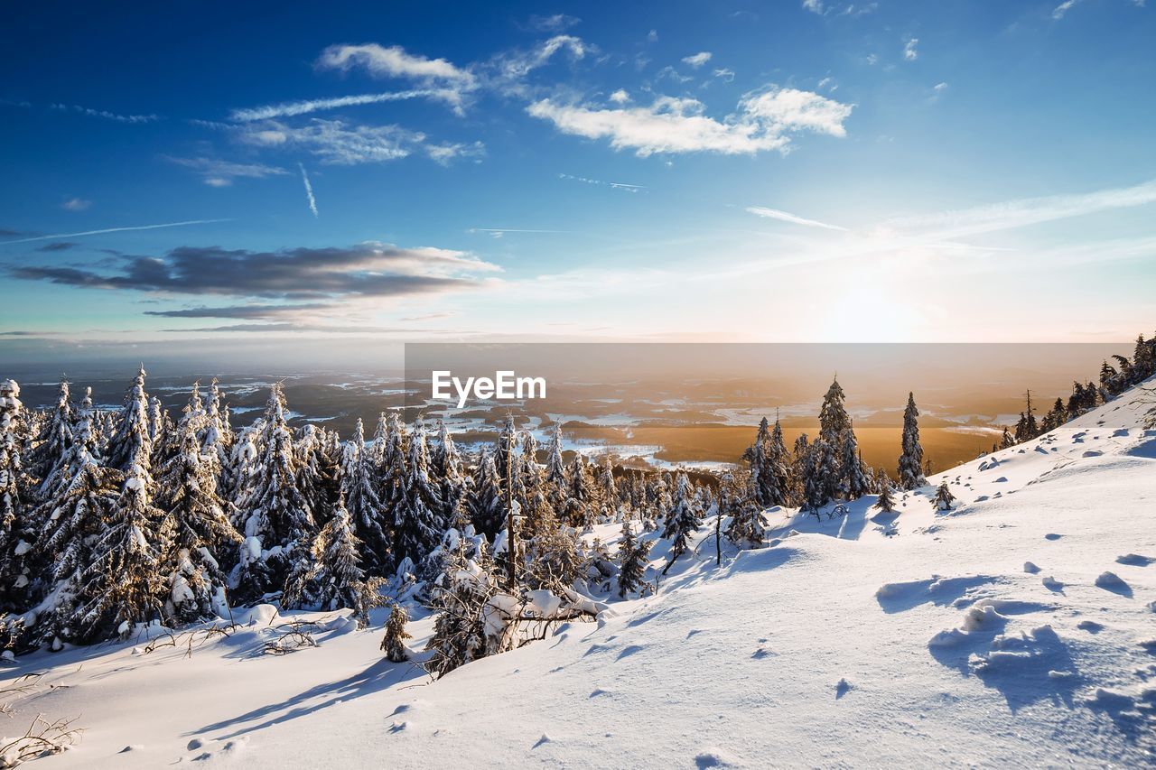 Snow covered field against sky during winter