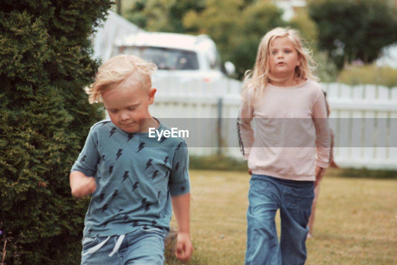 Siblings walking in yard