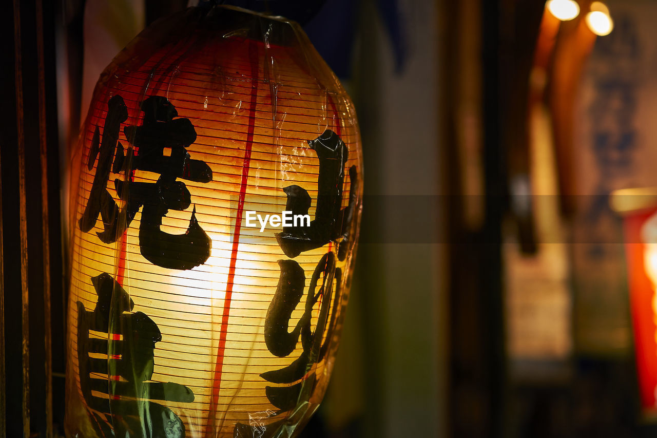 CLOSE-UP OF ILLUMINATED LANTERN ON WALL