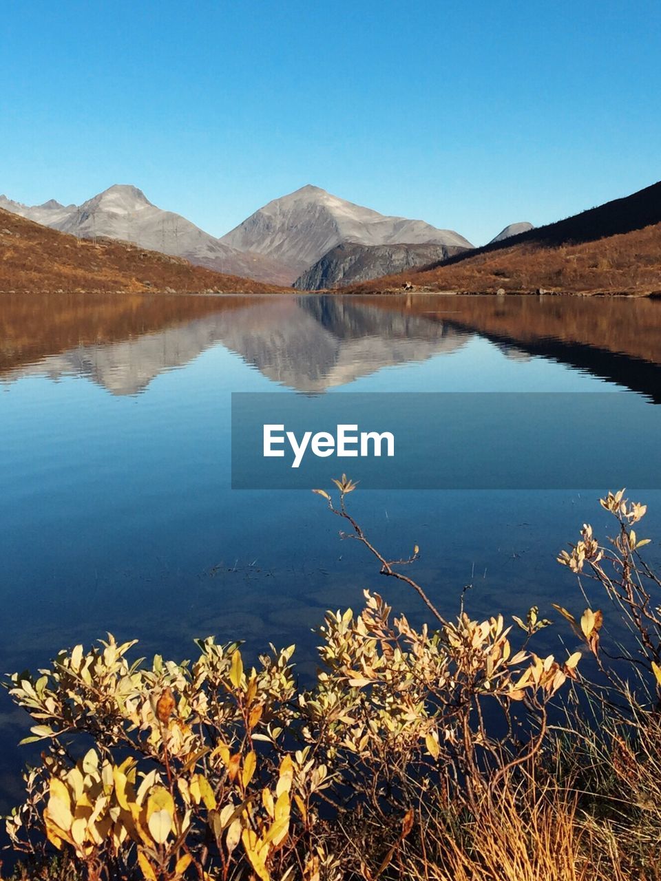 Scenic view of lake and mountains against clear blue sky