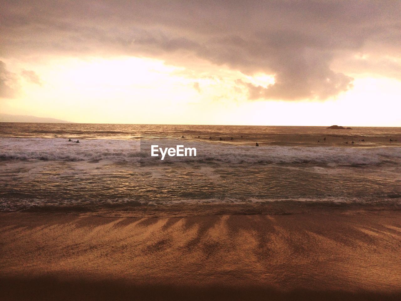 Scenic view of sea against cloudy sky during sunset