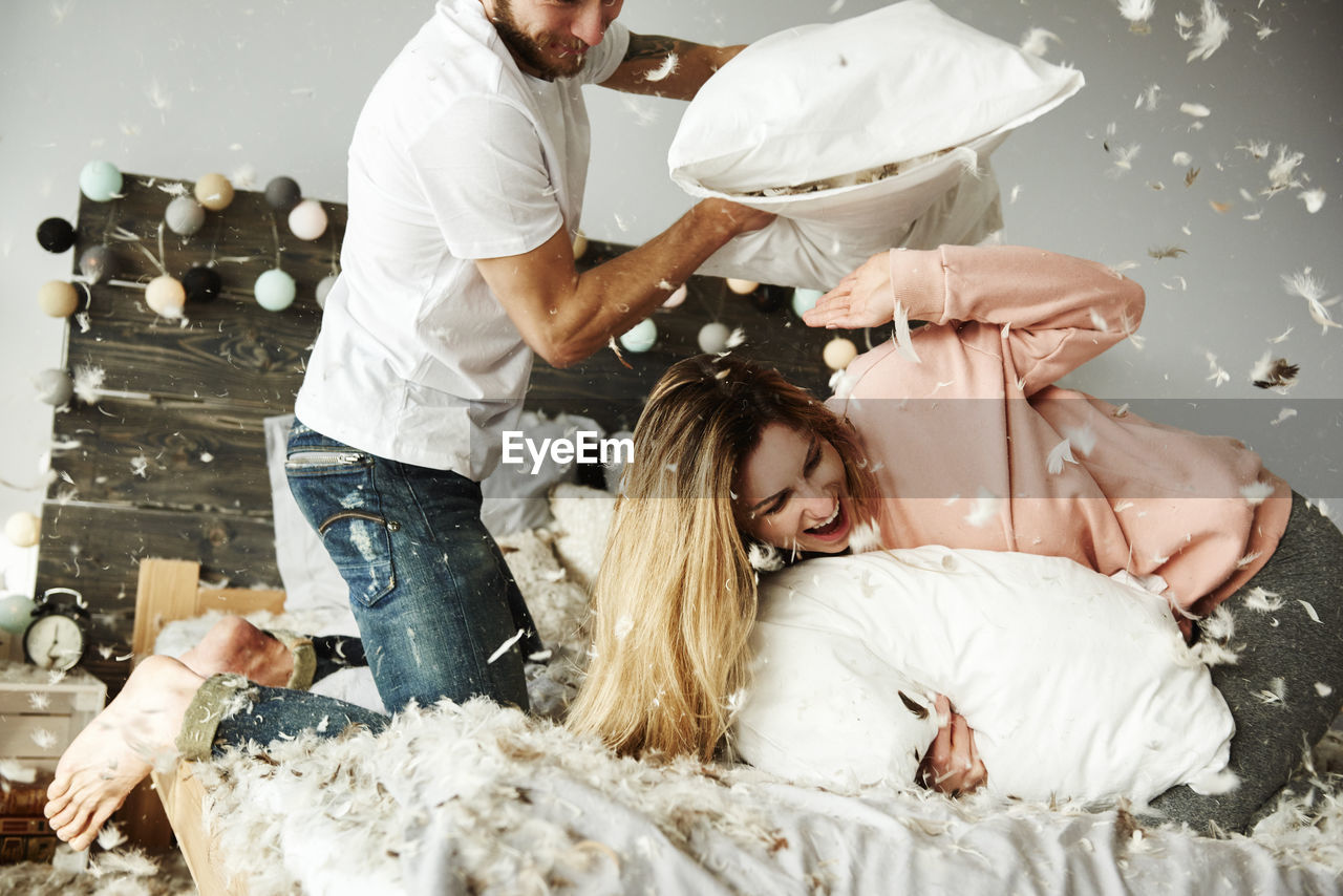Couple pillow fight on bed at home
